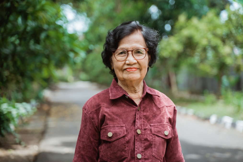 A grandmother wearing a red button up shirt with short black hair and glasses